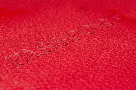 Red passport cover with letters on it. Macro close up.