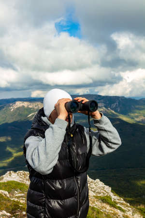 Man Binoculars Looking Mountain Cloudscape Traveling Conceptの写真素材