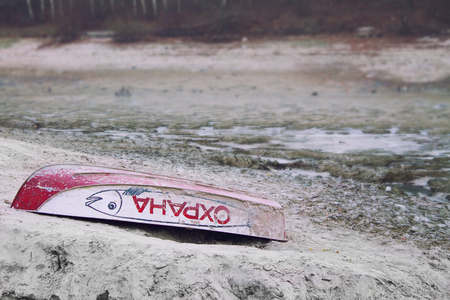 Old Upturned Boat red Color Lies on the Shore of the Dried Lake. The inscription on the side of the boat PROTECTIONの写真素材