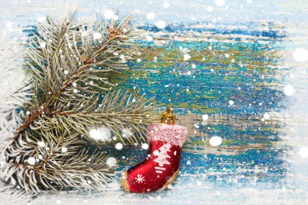 Christmas new year background. Red toy sock Santa Claus on wooden background and snow-covered spruce branches. Toned. Copy spaceの写真素材