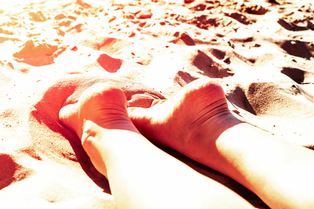 Female legs heels up on a sandy beach in a Sunny Tropical vacation concept of holiday and relaxation pekudei the sun. tinted .の写真素材