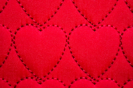 Abstract heart background On textiles, fabric stitched heart symbols in red. Handmade