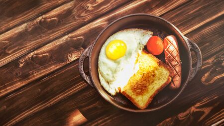 Austere and modest Breakfast. Scrambled eggs, toast and fried sausage in a cramped clay plate on an old wooden table.の写真素材
