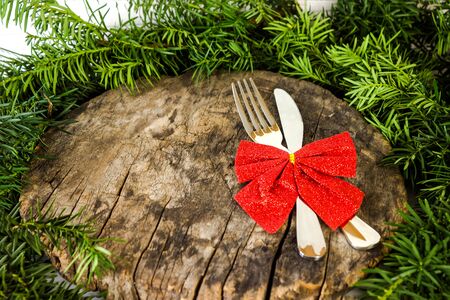 Christmas table setting with silverware, green pine branches and Christmas decorations on wooden natural background. Top view copy spaceの写真素材