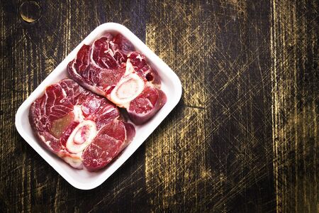 Raw ossobuco meat, two beef steak for cooking, black wood background. a traditional dish of Italian cuisine, which is a veal shank.Top view. Copy spaceの写真素材