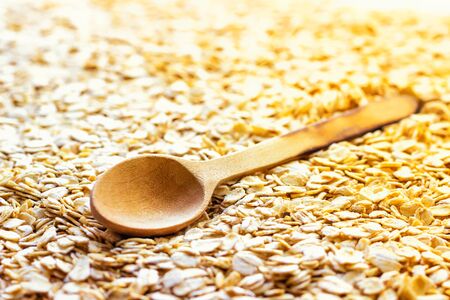 An old wooden spoon is lying on the scattered oatmeal. Vegetarian food. Nutrition for diseases of the digestive system. Conducting home Economics in the village and on the farmの写真素材