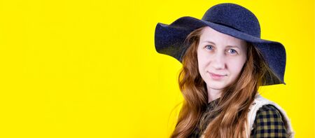 Banner Portrait of a young beautiful red-haired girl with long loose hair, gently looking at the camera. On a yellow background . The concept of human emotions. Copy space. Suitable for the designの写真素材