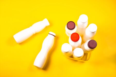Empty plastic yogurt bottles on a yellow background. Collection of waste food plastic packaging. Concept of plastic recycling environmental Ecology. Top view with copy space.の写真素材