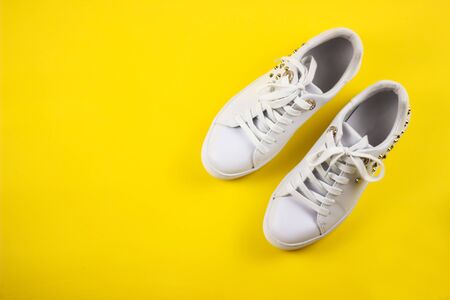 A pair of new white women's sneakers on a yellow background. The view from the top.の写真素材