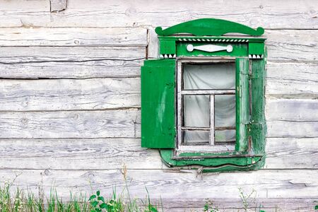 Part of the wall and green shutters in an abandoned rural wooden house..の写真素材