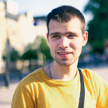Happy, surprised Young man, student, tourist, dressed in a yellow t-shirt, looking away, against the backdrop of the city landscape. Happy young people. Concept of youthの写真素材
