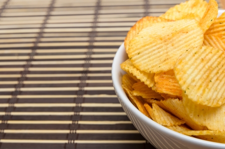 Potato chips in white bowl on bamboo matの写真素材