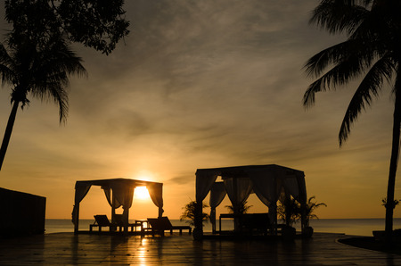 Sunrise view at hotel resort. Relaxing holiday landscape. Two beach tent and chairs with palm tree.の写真素材