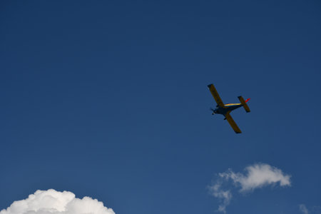 Small airplane flying in the blue sky with white clouds on a sunny dayの写真素材