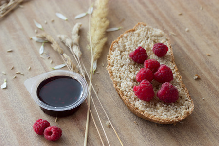 bread raspberries jam and ears on wooden tableの写真素材