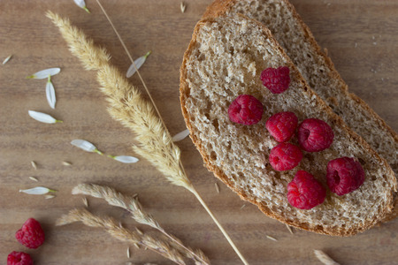bread raspberries and ears on wooden tableの写真素材