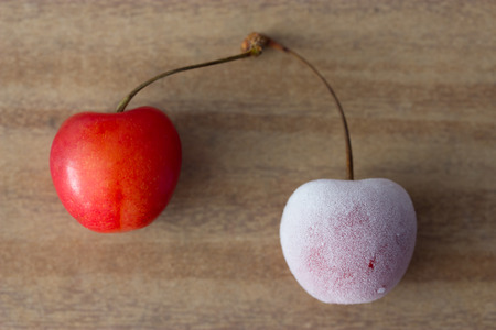 two cherries: one frozen and one freshの写真素材