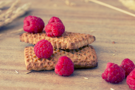 cookies with raspberries and ears on wooden table, tonedの写真素材