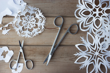 handmade paper snowflakes and scissors on tableの写真素材