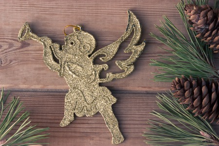 golden Christmas cherub and Christmas tree branches on wooden tableの写真素材
