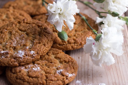 Homemade oatmeal cookies and white flowers on wooden backgroundの写真素材