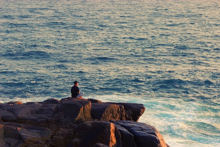 Man meditating on a rock at the sea. copy spaceの写真素材