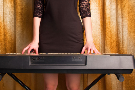 unrecognizible girl musician playing on electronic piano. dolden backgroundの写真素材