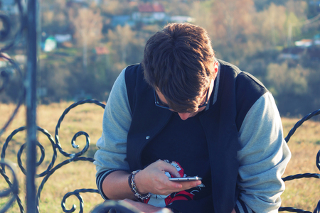 Outdoor portrait of modern young man with mobile phone in the parkの写真素材