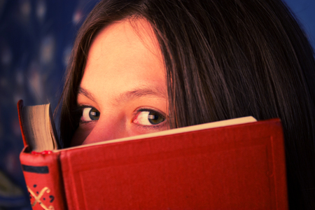 smiling girl with a book looking over book coverの写真素材