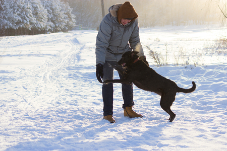 Man playing with black dog at winter fieldの写真素材