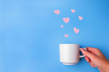 white cup on blue background with heartsの写真素材