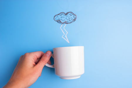 rain pouring in coffee cup on blue backgroundの写真素材