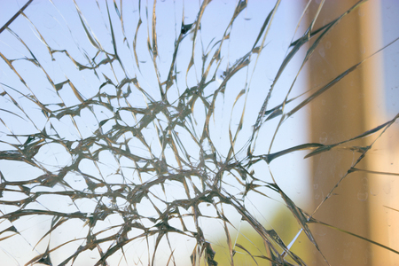 broken glass window reflecting blue sky. close up