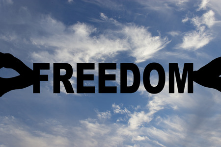 hands holding freedom text against the sky