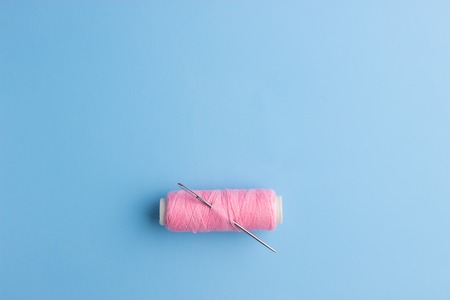 pink thread and needle on blue backgroundの写真素材