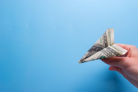 Flying paper plane with dollar banknote holding in handの写真素材