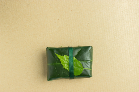 gift box with a green leaf on it on wooden backgroundの写真素材