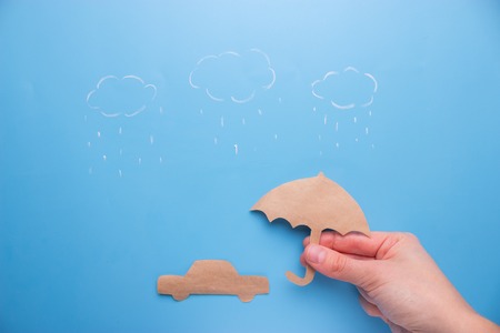 Hand holding an umbrella to protect a car - insurance conceptの写真素材