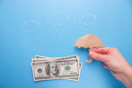 Save money concept. 100 dollar bills under umbrellaの写真素材