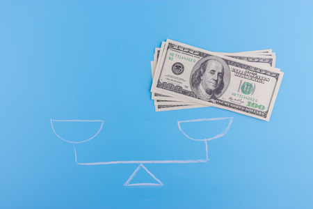 money on one of the scalepans on blue backgroundの写真素材