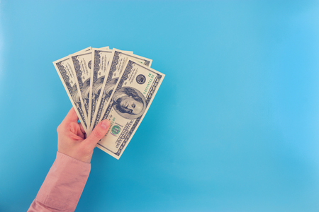 hand hold dollar bills on blue background