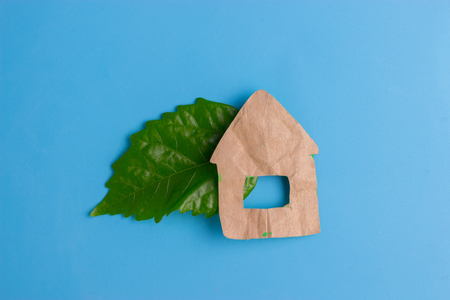 paper eco house with green leaf on blue backgroundの写真素材