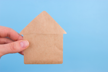 hand holding paper house on blue backgroundの写真素材