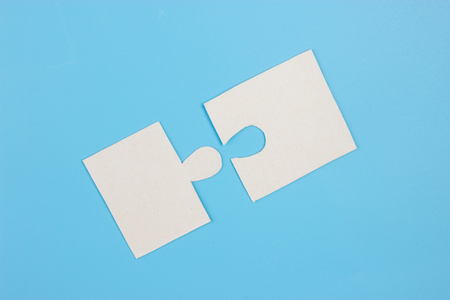 Two blank white puzzle pieces in handsの写真素材