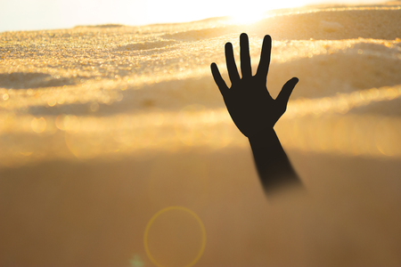 Hand on a beach sinking or drowningの写真素材