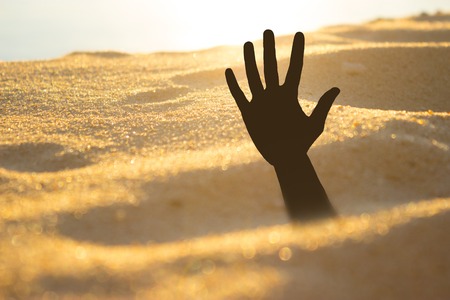 Hand on a beach sinking or drowningの写真素材