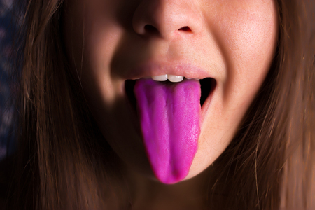 Close-up portrait of woman shows tongue.