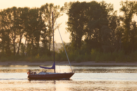 Beautiful sunset. distant sailboat. sailing on the river