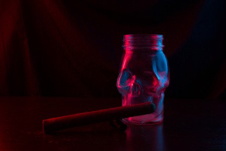 The glass skull smokes a pipe. neon light