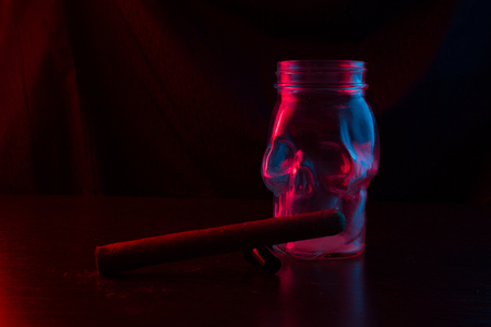The glass skull smokes a pipe. neon lightの写真素材